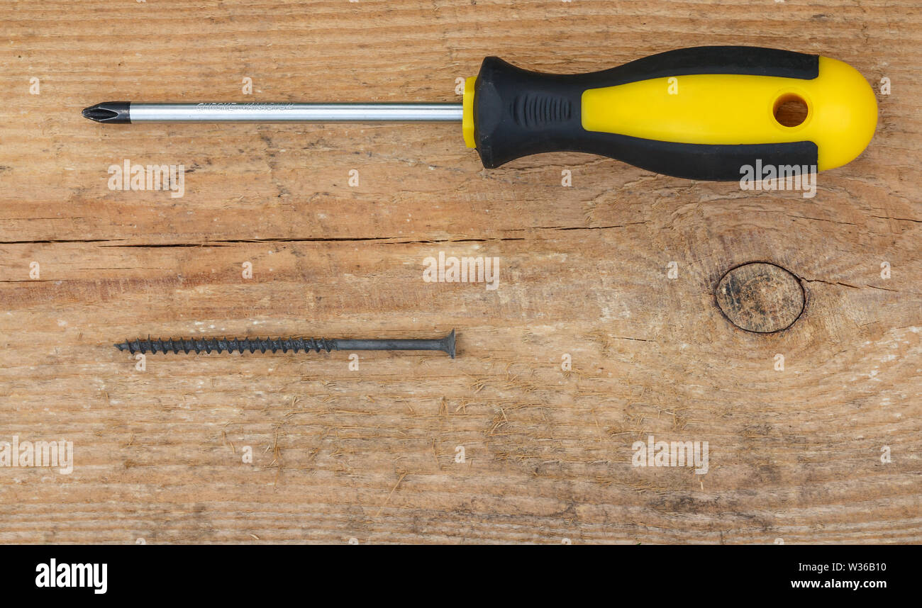 Werkzeuge. Schraubendreher und einem schwarzen Schraube auf Holz- Hintergrund. Ansicht von oben. Stockfoto