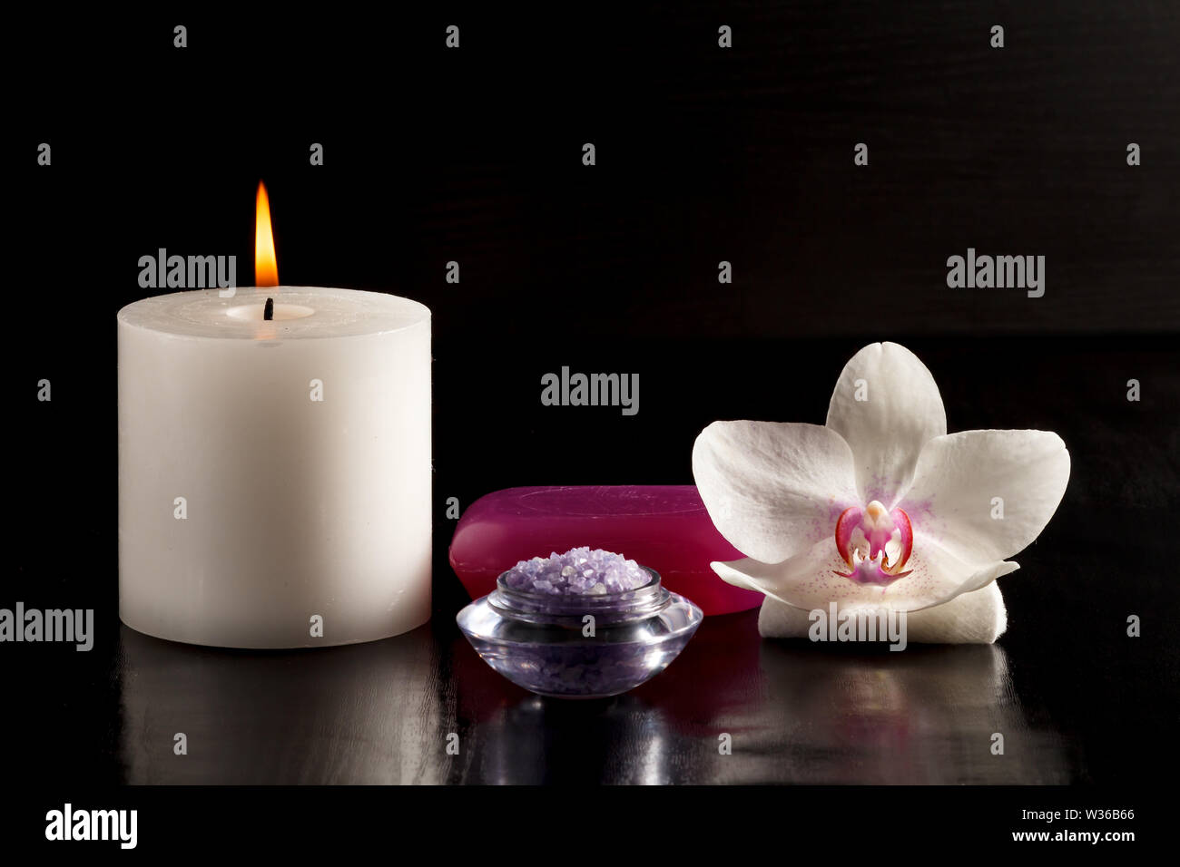 Brennende Kerze, Schale mit Salz, Seife und White Orchid Flower für Spa auf  dem schwarzen Hintergrund Stockfotografie - Alamy
