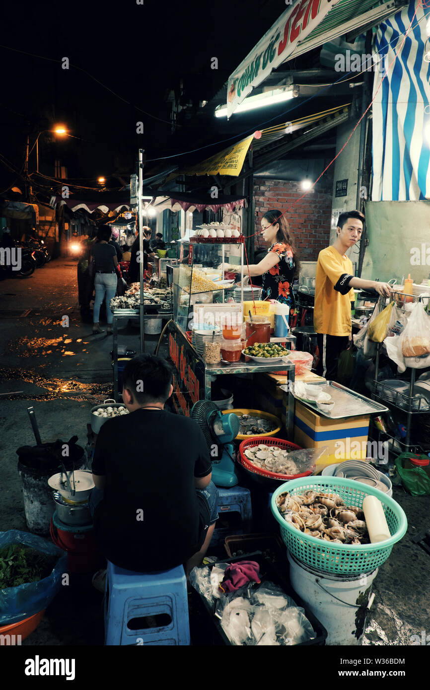 Gruppe von Diners Essen im Restaurant im Freien Nacht in Food Street, geschäftige Atmosphäre auf der Straße wenn Leute gehen in Abendessen Zeit, Vietnam Stockfoto
