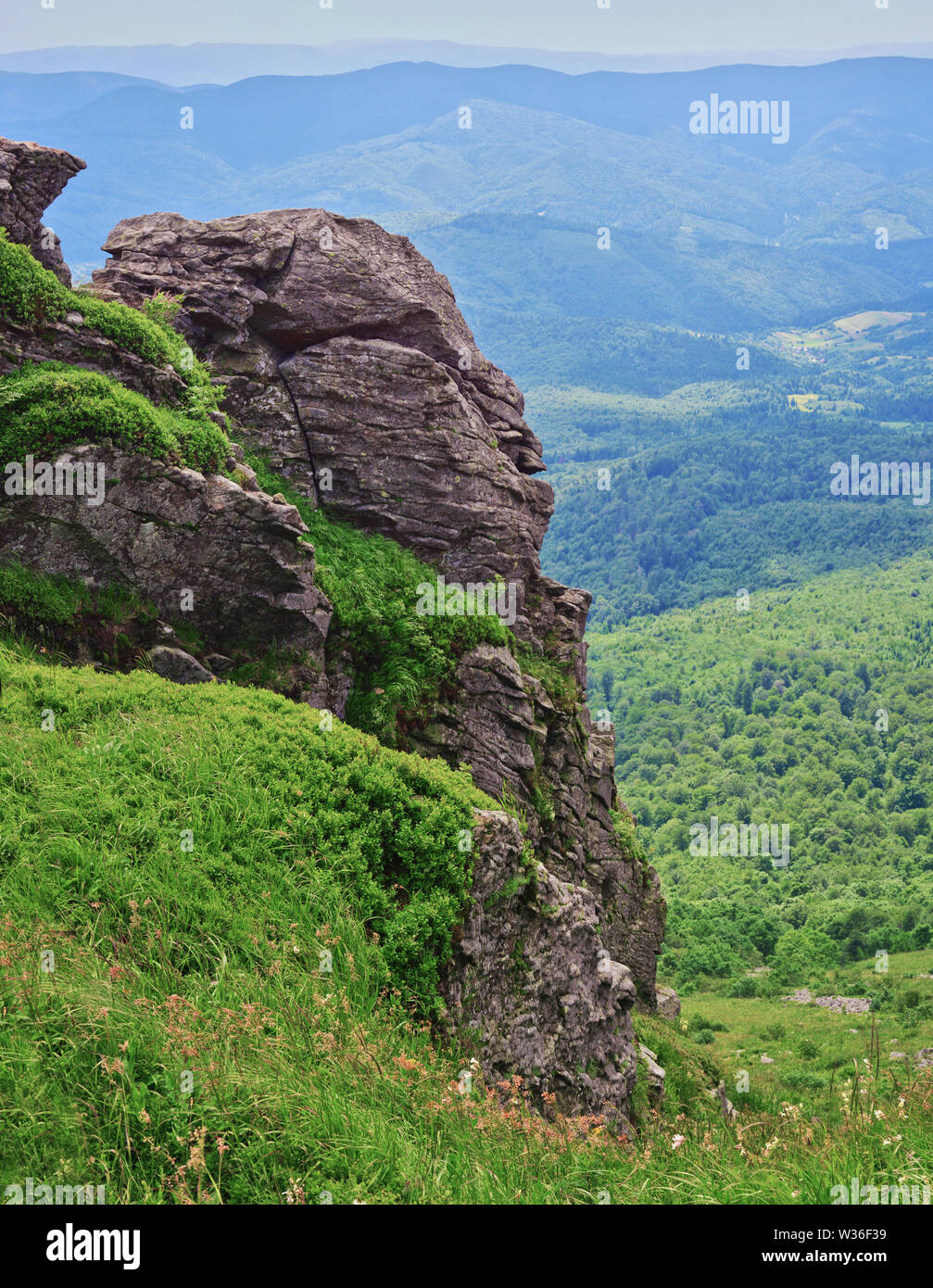 Felsen auf Pikuy Berg gegen das Tal unter majestätischen Green mountain Hills in Wiesen und Wald bedeckt. Bewölkt Sommer Tag im Sommer. Ukraine, Lv Stockfoto