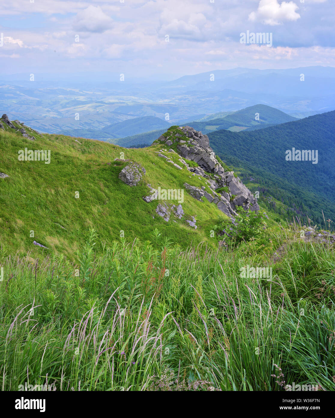 Felsen auf Pikuy Berg gegen das Tal unter majestätischen Green mountain Hills in Wiesen und Wald bedeckt. Bewölkt Sommer Tag im Sommer. Ukraine, Lv Stockfoto