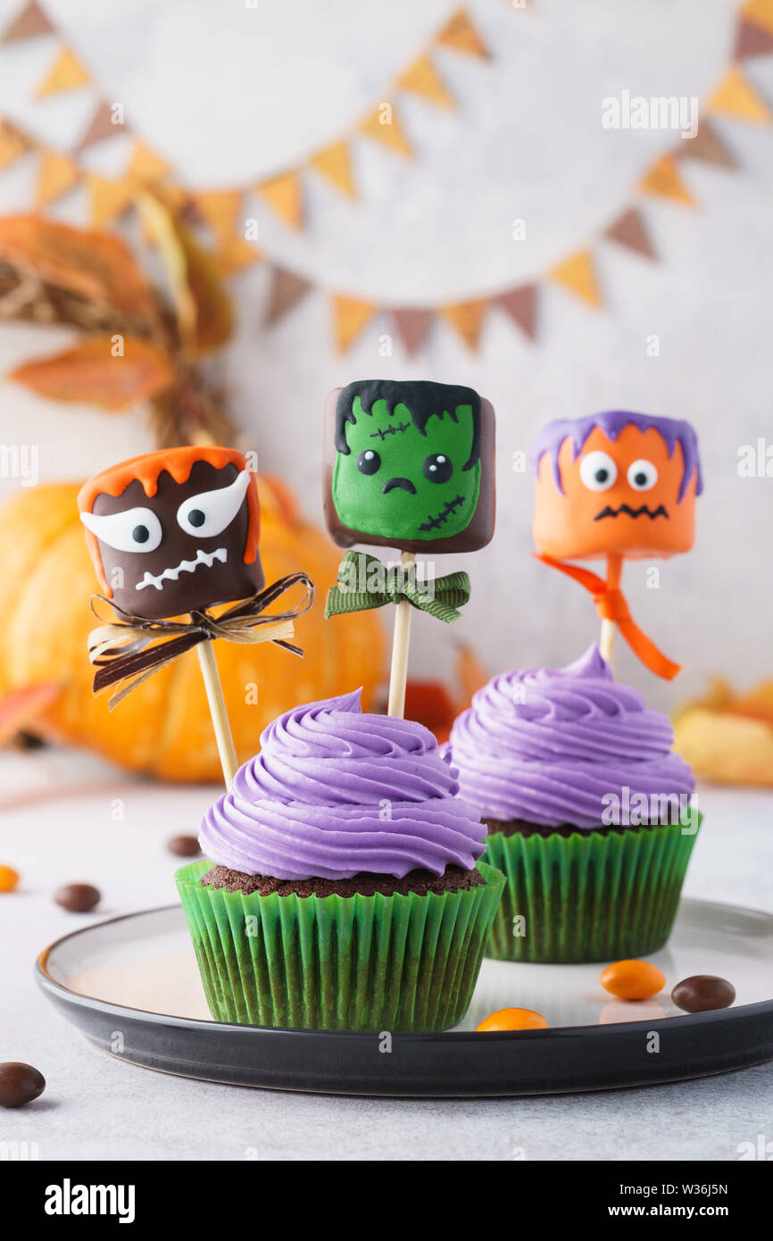 Festliche Halloween cupcakes dekoriert mit Marshmallow in Schokolade oder Kuchen und Süßigkeiten. Lustige monster Gesicht behandelt. Stockfoto