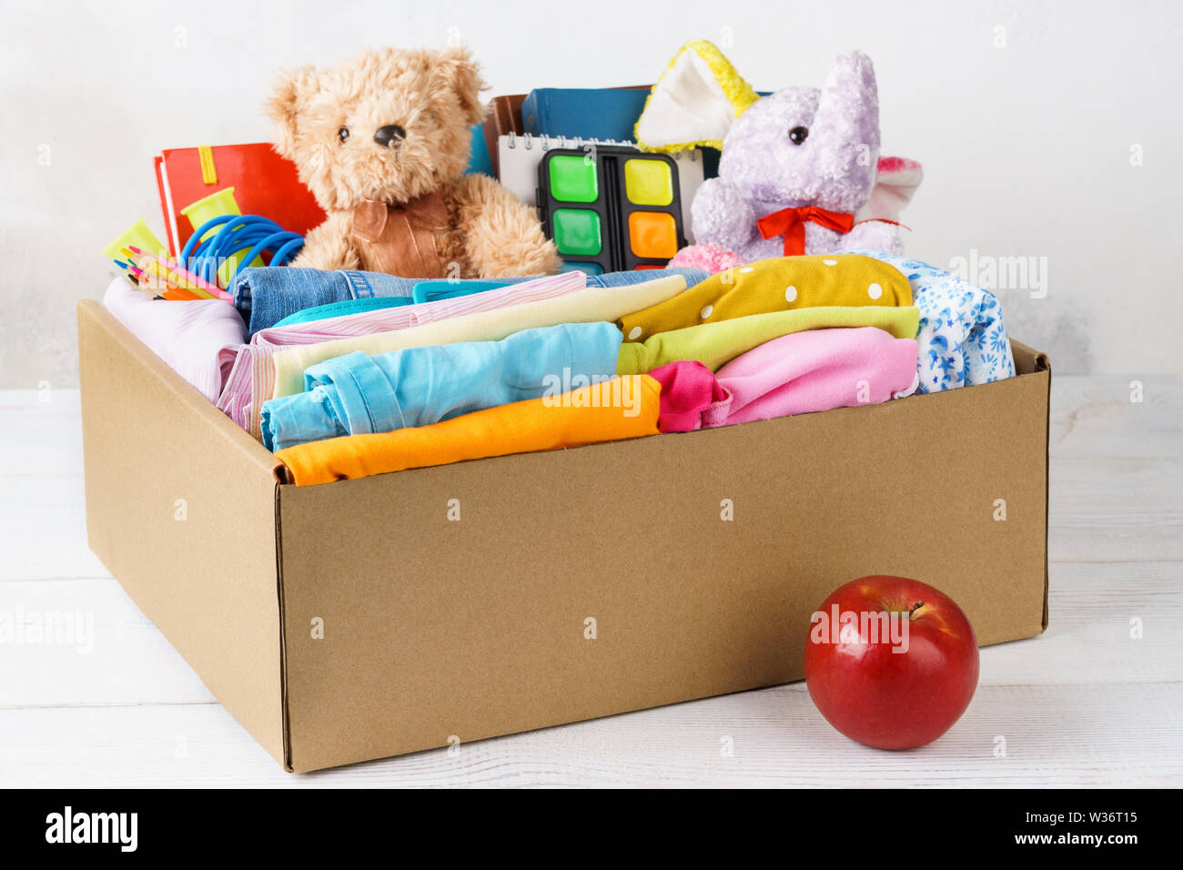 Bunte legere Kleidung, Schreibwaren und Spielwaren in einem Karton für den Versand oder Spenden. Zurück zum Konzept der Schule. Stockfoto