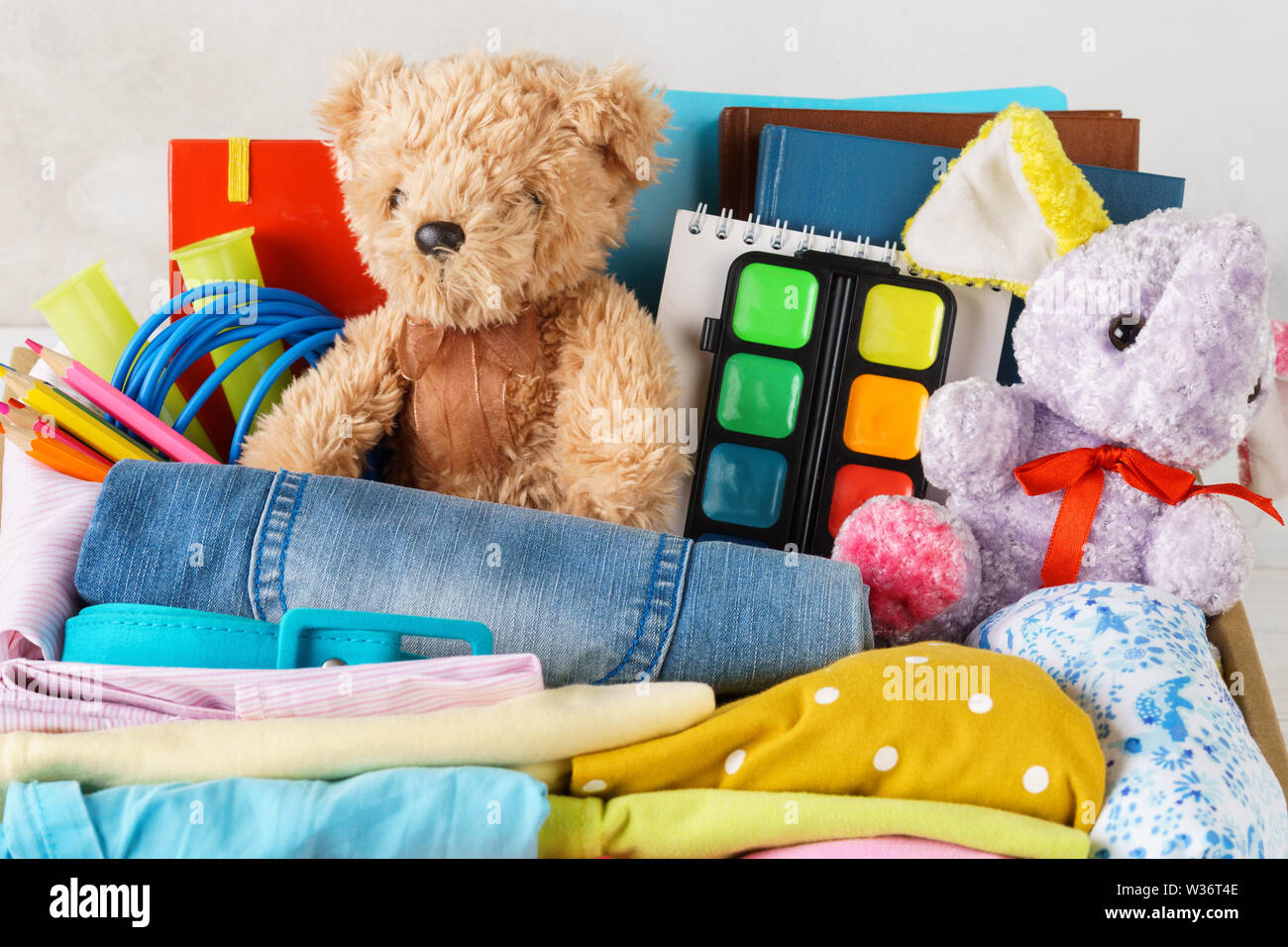 Bunte Kleidung für Kinder und Jugendliche, Spielwaren und Schreibwaren. Zurück zu Schule oder Spende Konzept. Stockfoto