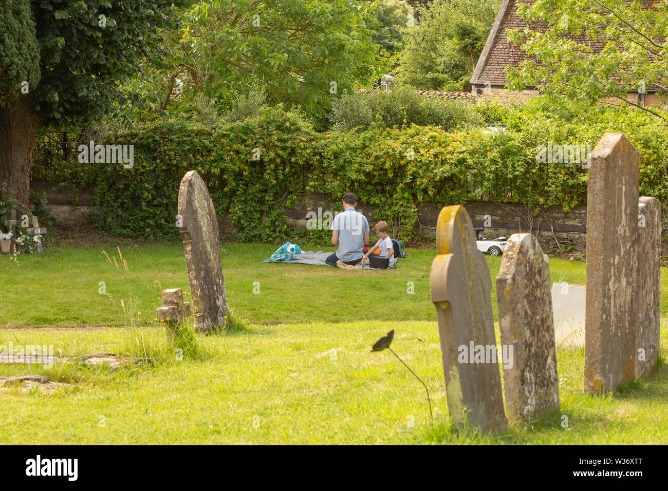 Ein Mann und sein Sohn haben ein Picknick inmitten Grabstein in der Kirche, Hof Stockfoto