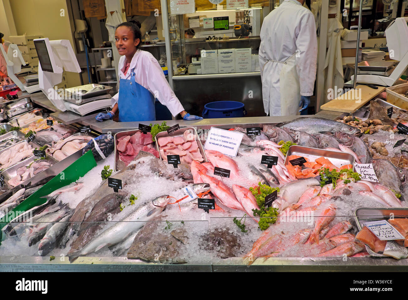 Cardiff Central Market junge Frau, die bei E. Ashton Fishmongers arbeitet und Meeresfrüchte an der Theke für frischen Fisch im Zentrum von Cardiff, Wales, UK, verkauft KATHY DEWIT Stockfoto