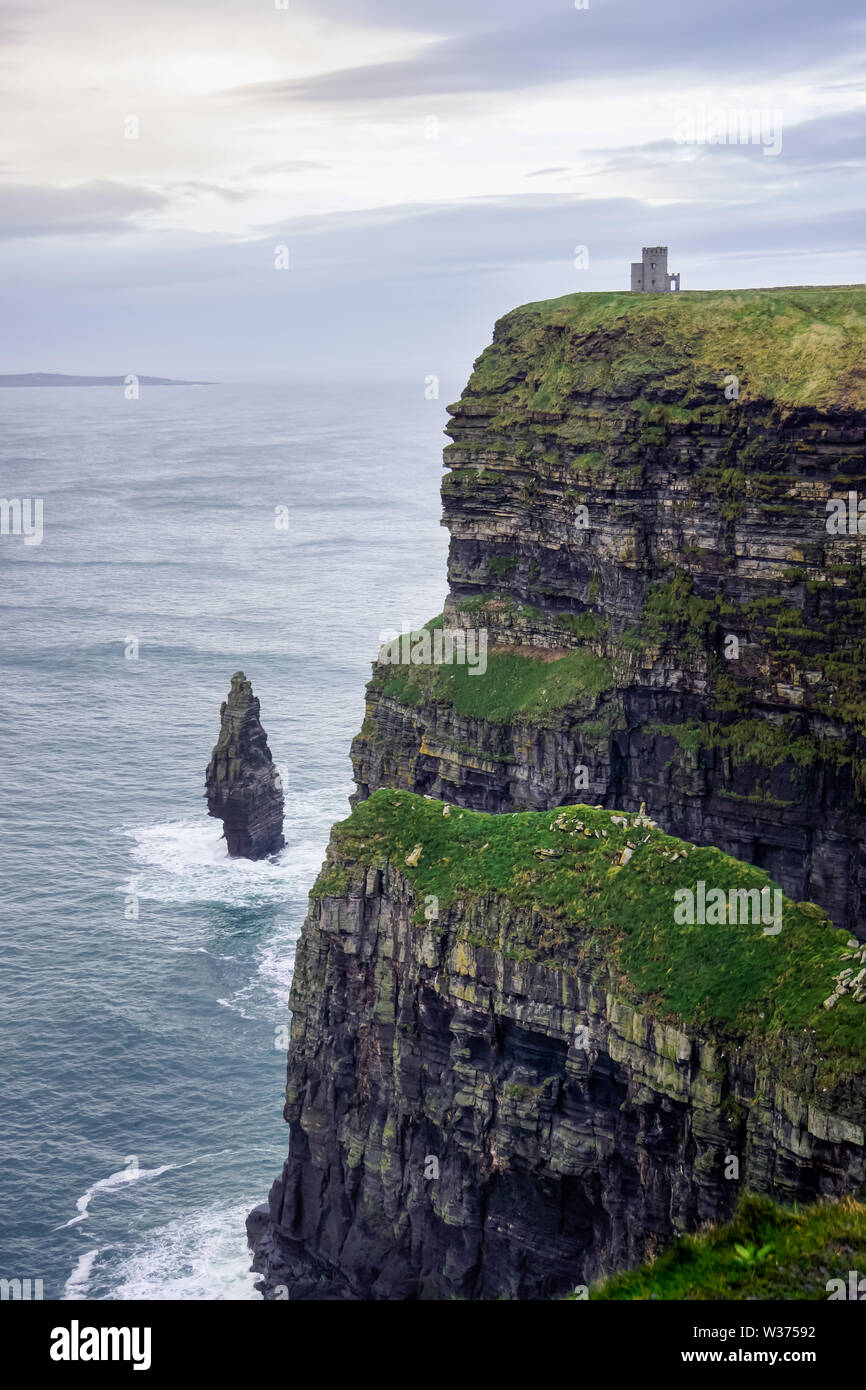 Die Klippen von Moher, die in den wilden Atlantik mit Ruinen des Turms am Rande der Klippe Stockfoto