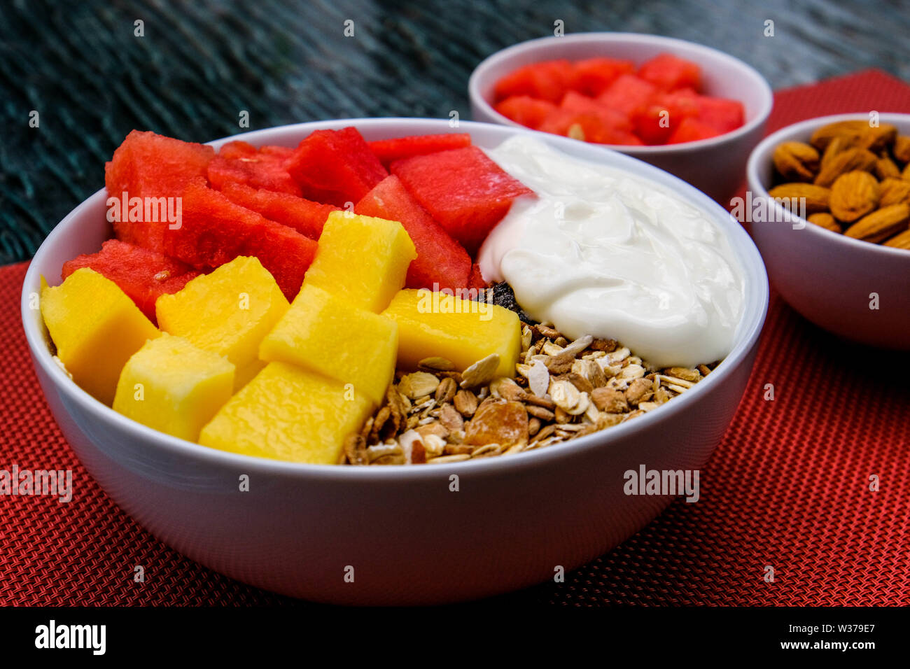 Gesunde vegetarische Frühstück Schüssel mit Joghurt, Müsli, Cornflakes, Melone und Mango Stockfoto