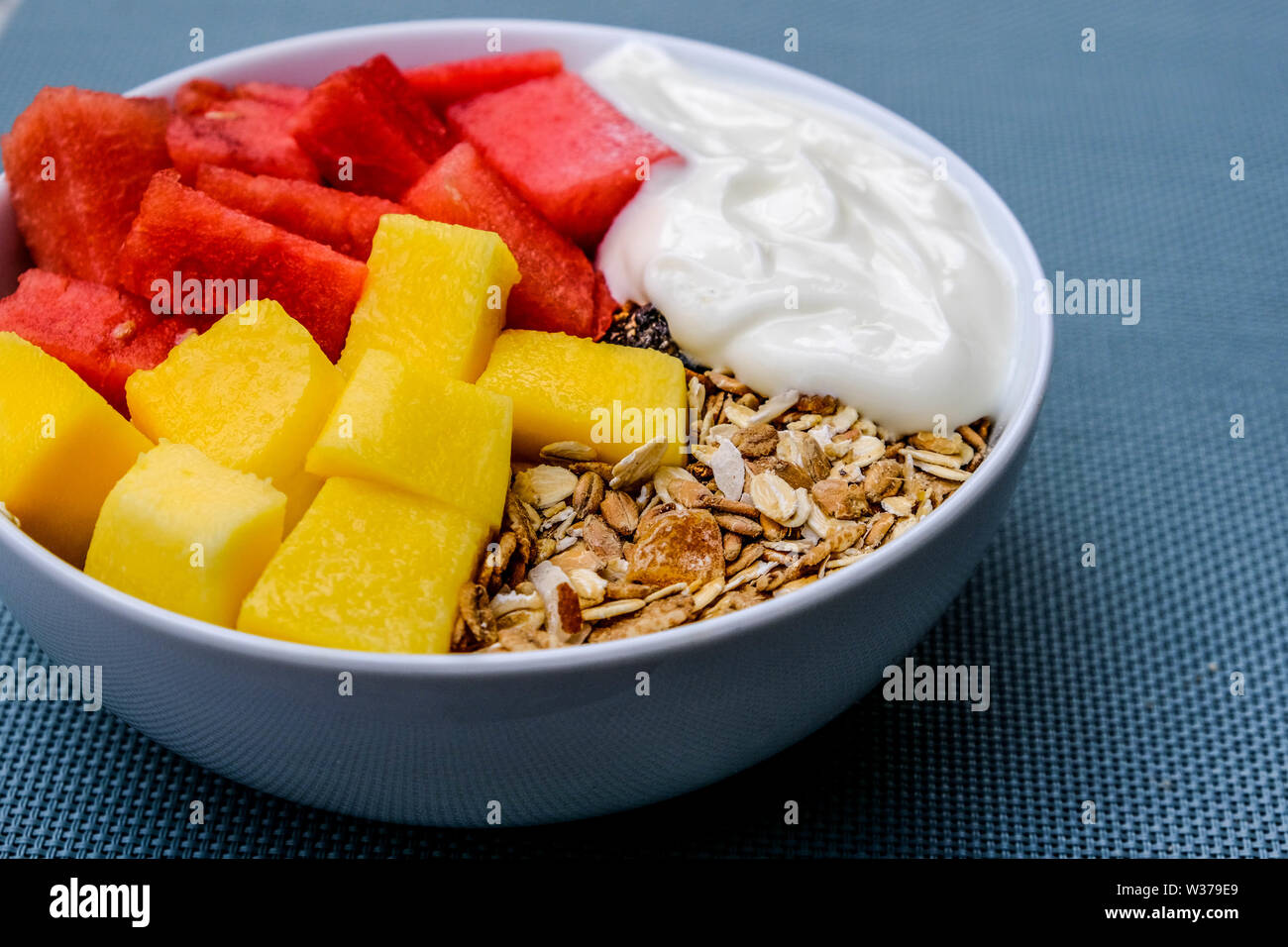 Gesunde vegetarische Frühstück Schüssel mit Joghurt, Müsli, Cornflakes, Melone und Mango Stockfoto