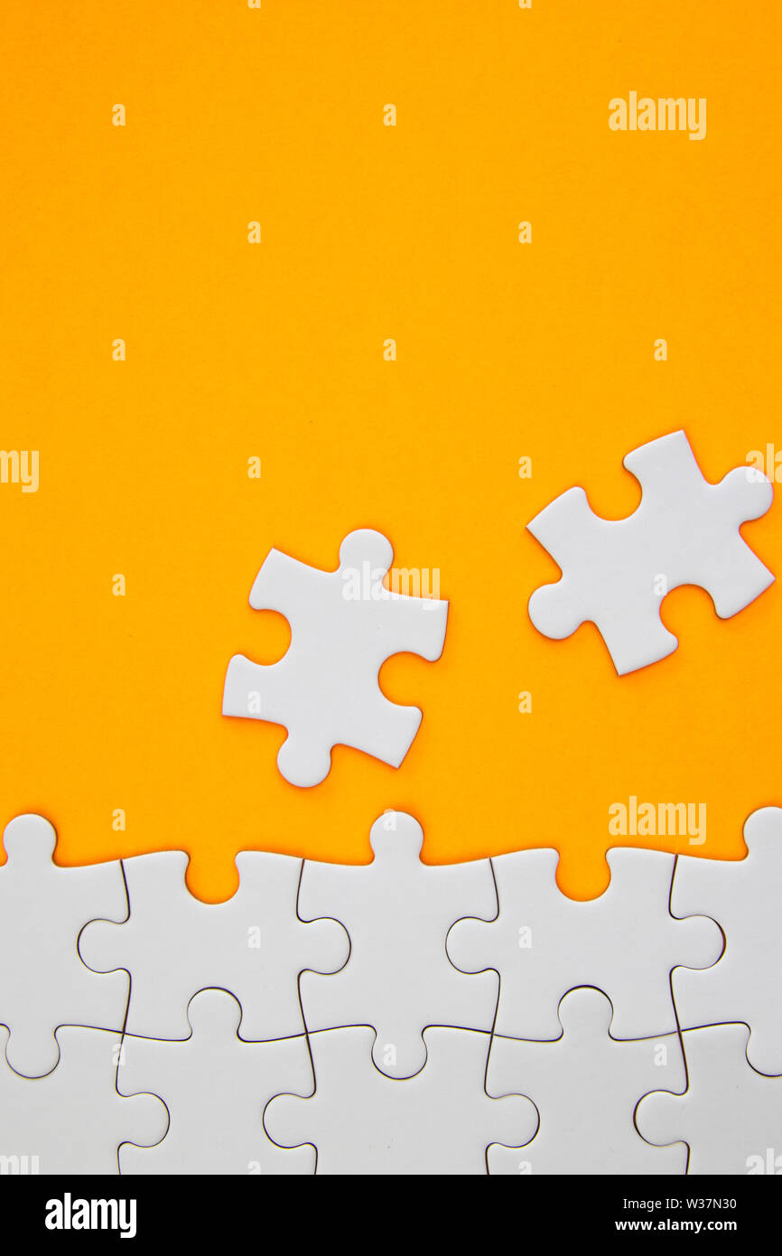 Weiß puzzle Stücke auf orange Hintergrund mit negativen Raum Stockfoto
