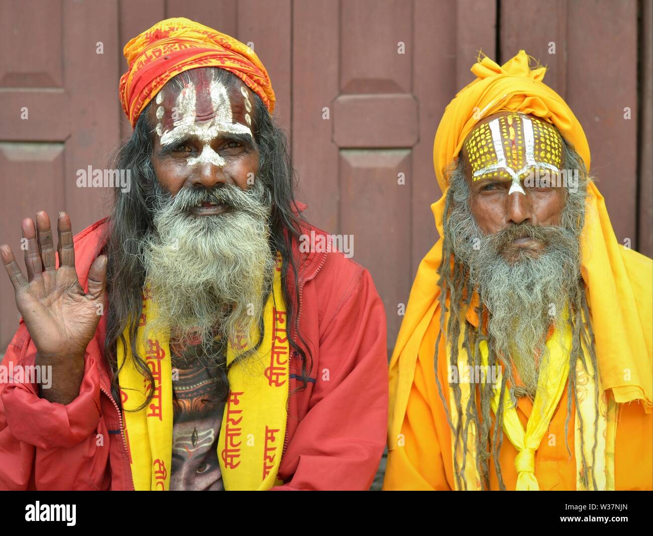 Zwei alte Nepalesische Vaishnavite sadhus (heilige Männer, die Anbetung Vishnu) mit bemalten Stirn tragen traditionelle rote und gelbe Outfit und für die Kamera posieren. Stockfoto