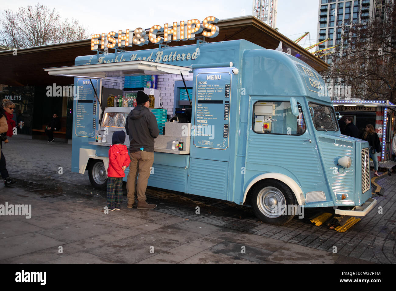 Mann und Kind stehen an der Theke eines traditionellen alten Britischen Fisch und Chip van in London, Großbritannien Stockfoto