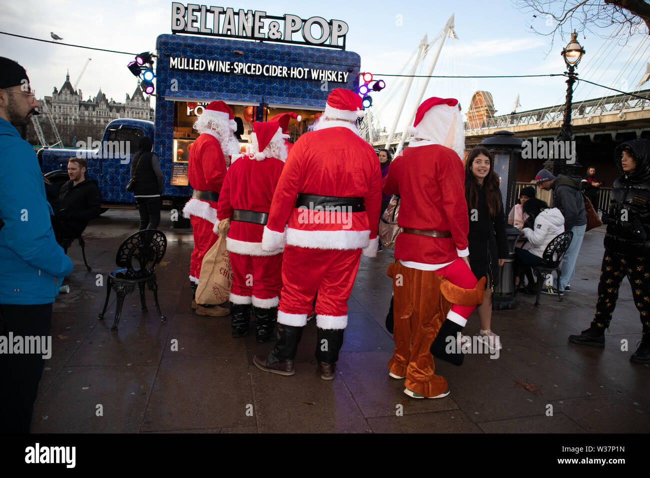 Der Weihnachtsmann steht neben einem Alkohol Getränke Straßenhändler in alten blauen Van, der verkauft Glühwein, gewürzter Apfelwein und Hot whisky London UK Stockfoto