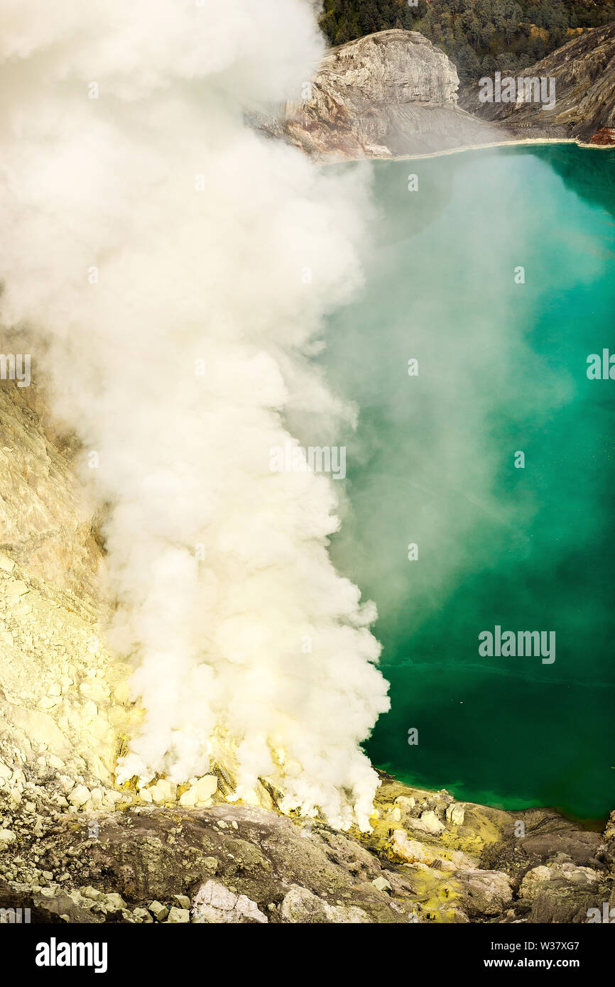 Krater eines Vulkans mit einem grünen Schwefelsäure See vulkanischen Ursprungs und vulkanische Rauch. Blick auf den rauchenden Vulkan Kawah Ijen in Indonesien Stockfoto