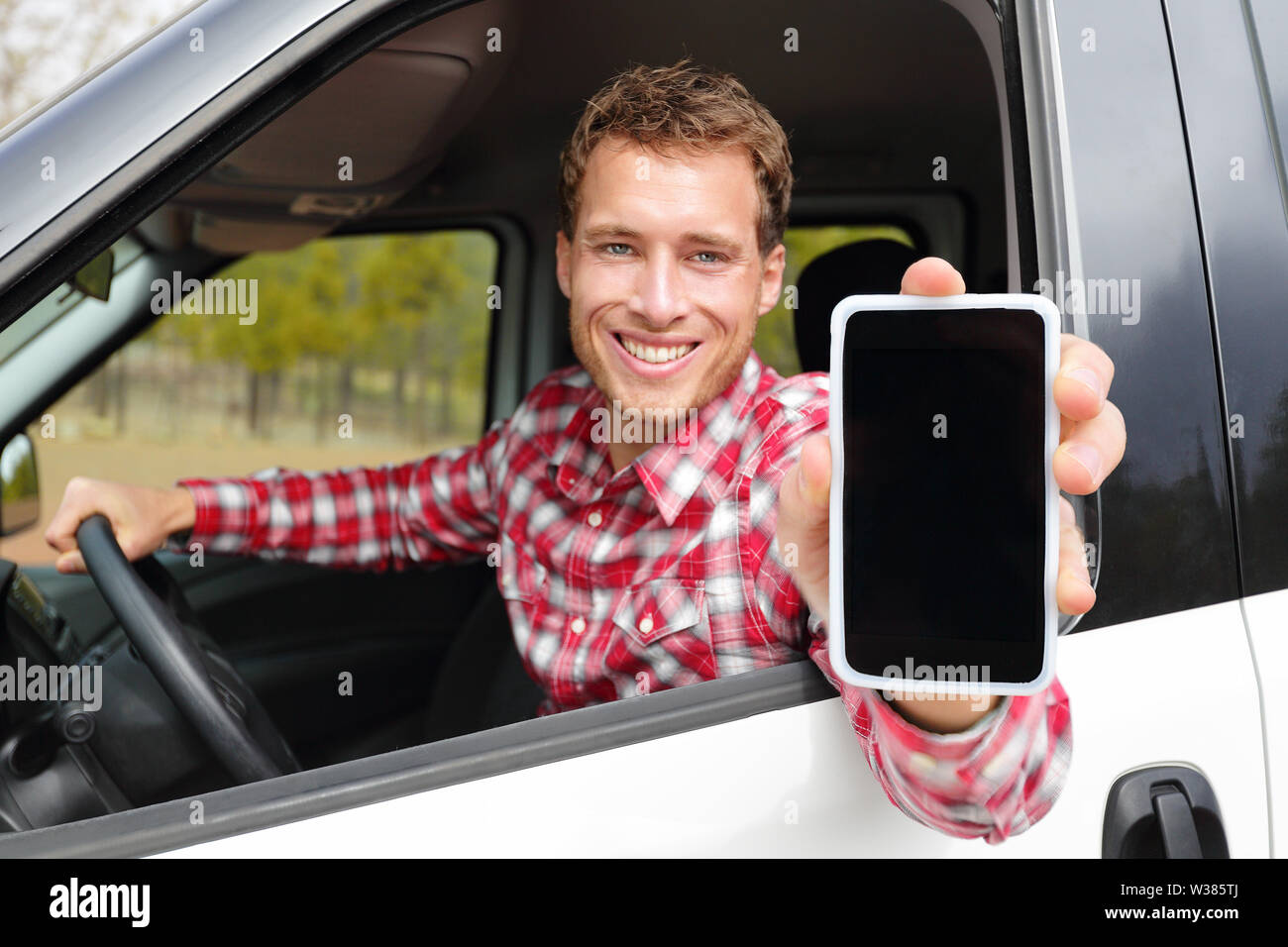 Smartphone mann Auto übersicht App auf dem Bildschirm lächelte glücklich. Männliche Fahrer mit 4 g Apps anzeigen leer Leer Touchscreen im Fahrersitz sitzen. Fokus auf und auf dem Bildschirm zu kopieren. Stockfoto