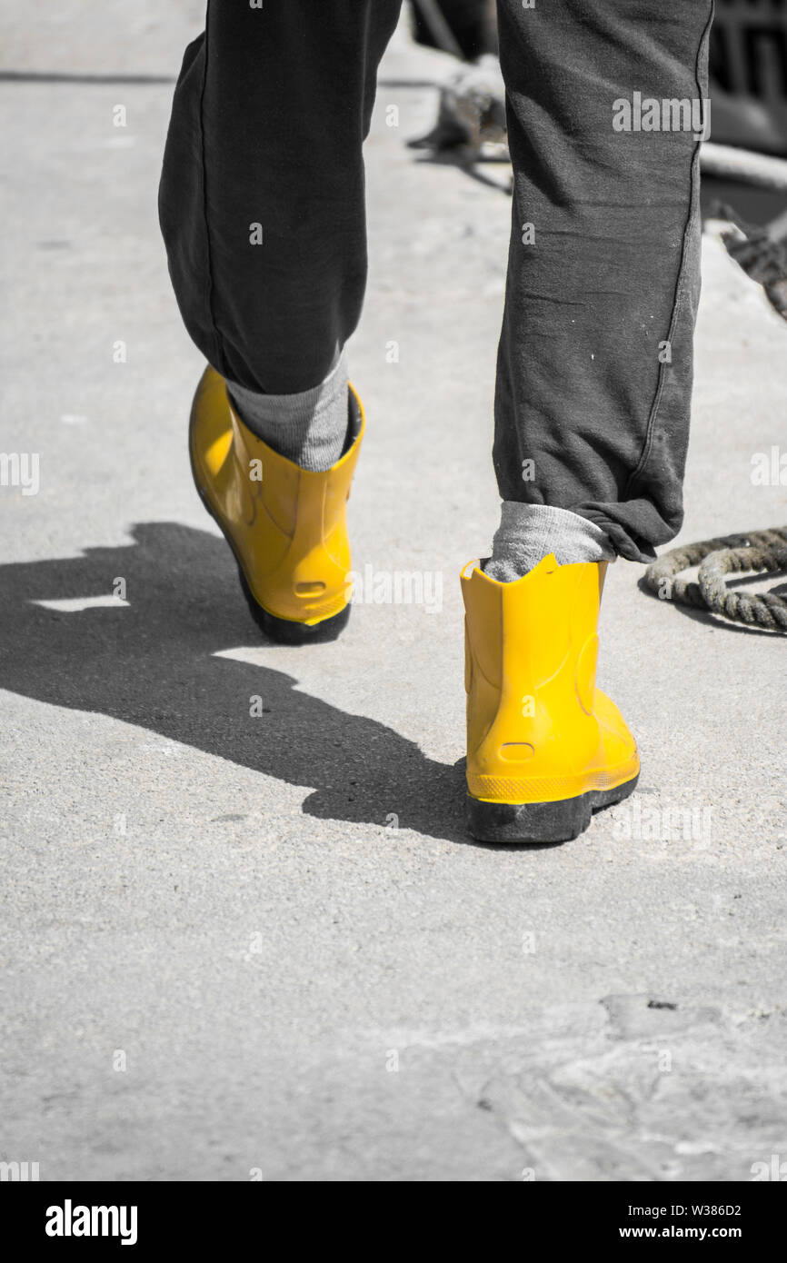 Fischer ist zu Fuß in den Häfen inyellow Gummistiefel, Gummi Stiefel ampng  Seile auf einem sumer Tag in Griechenland Stockfotografie - Alamy