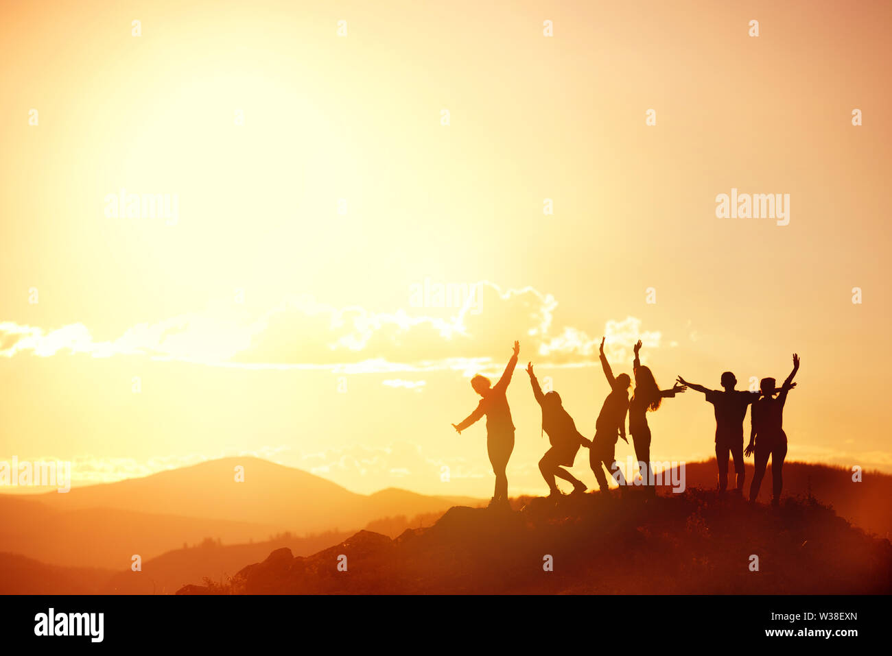 Große Gruppe von Freunden oder der großen Familie Silhouetten steht und Spaß bei Sonnenuntergang in den Bergen. Platz für Text Stockfoto