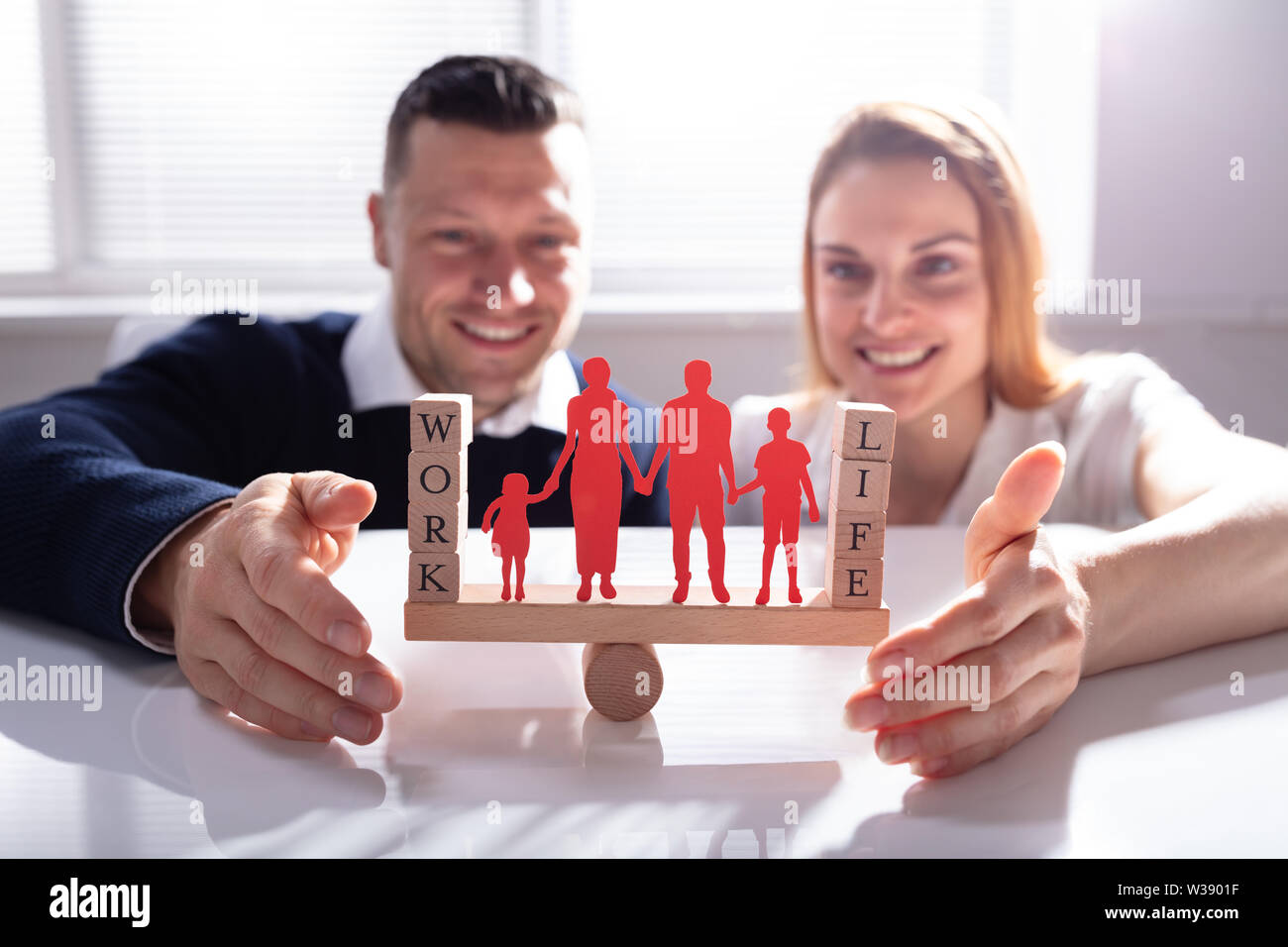 Paar Arbeits- und Privatleben mit Familie Zahlen auf Wippe über Schreibtisch Stockfoto