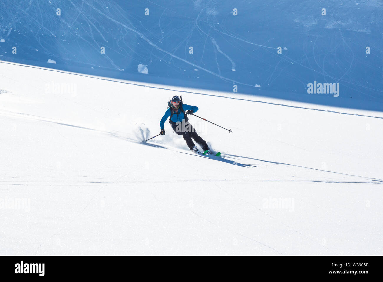 Backcountry skier auf sanften sonnigen Hang unter steilen Klippen von frischen Alaska Frühling Schnee. Stockfoto
