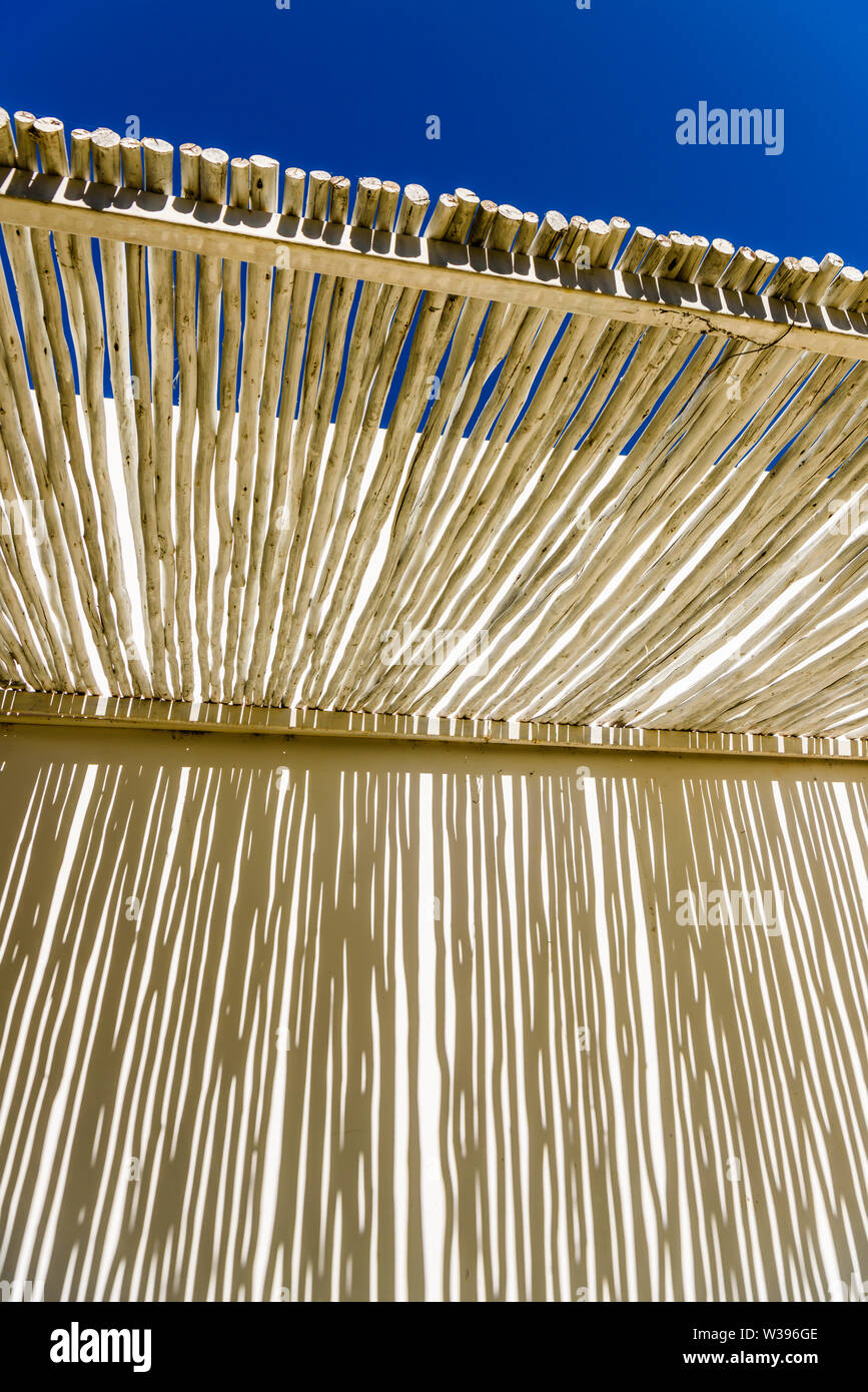 Abstrakte Schatten auf einer weißen Wand durch den Overhead Vordach von rustikal Holz, in einem Hotel in Namibia Stockfoto