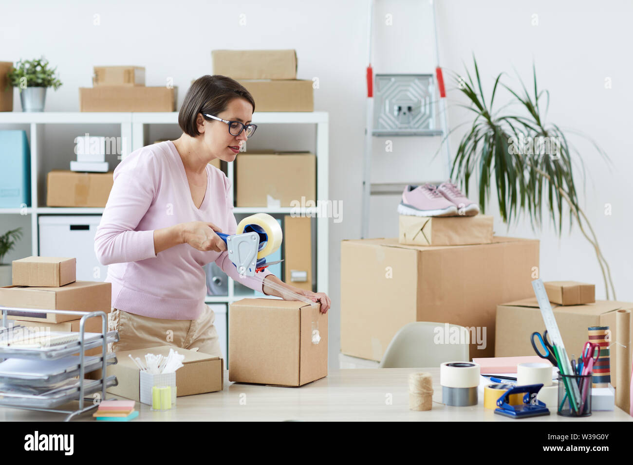 Junge Manager in casualwear Karton mit online Bestellung von Client mit cellotape im Büro Stockfoto