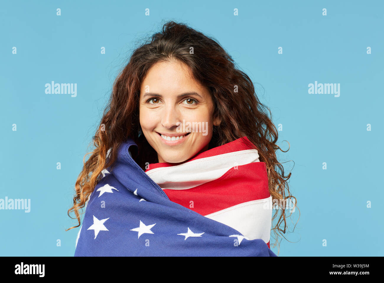 Junge attraktive Frau mit dunklen Lange wellige Haare eingewickelt in die nationale amerikanische Flagge Stockfoto