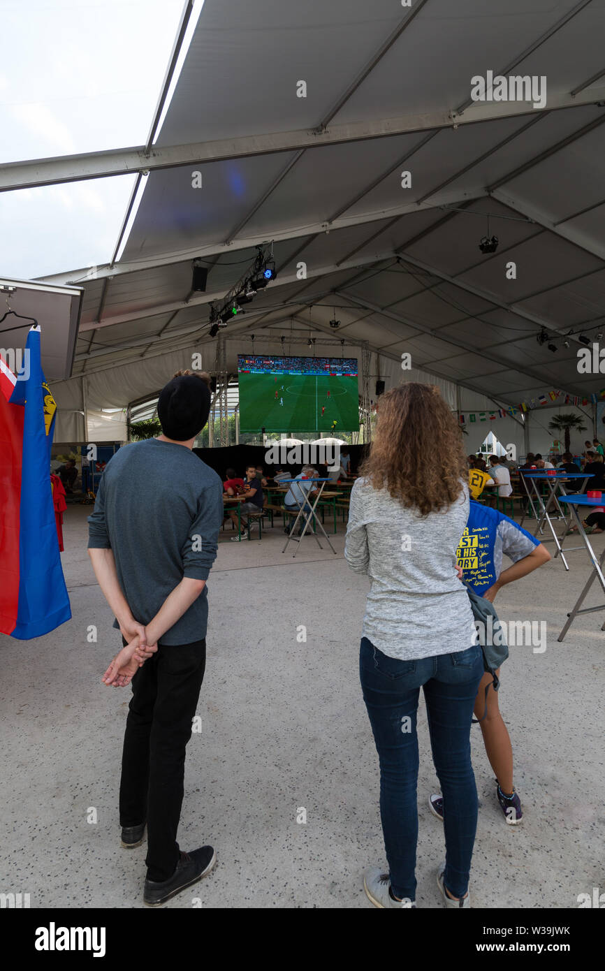 Auf dem Städtle in Vaduz, Liechtenstein, halten die Menschen an, um ein Spiel der FIFA-Weltmeisterschaft 2018 auf dem Großbildfernseher zu sehen. Stockfoto