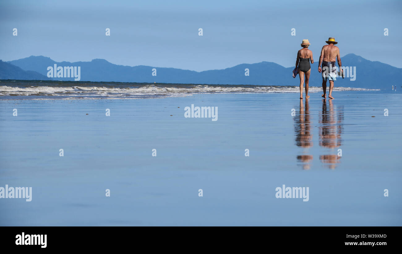 Das Leben ist ein Strand in Australien vor allem auch sehr gut für ältere Menschen, in den Ruhestand zu treten. Ein altes Ehepaar Spaziergang entlang der Sand in Mission Beach North Queensland. Stockfoto