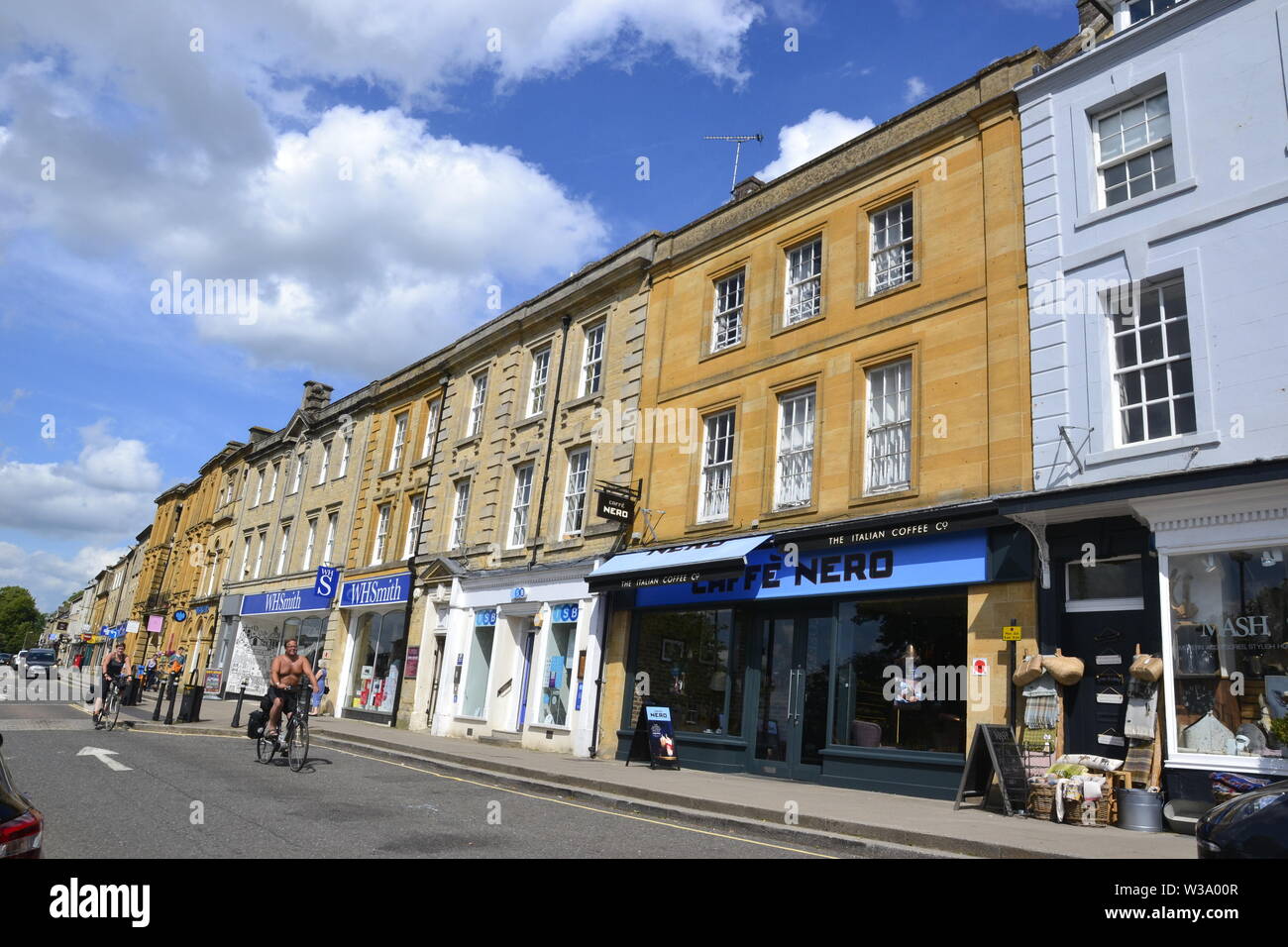 Menschen radfahren Vergangenheit die Geschäfte in Chipping Norton, Oxfordshire, UK. Teil des Cotswolds. Stockfoto