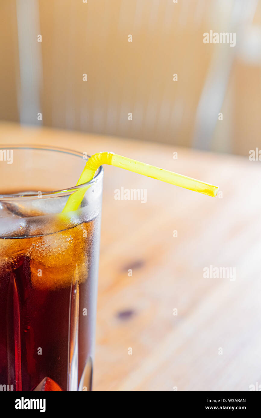 Eisig kalten Getränk im Glas, Nahaufnahme. Glas kühles Mineral Drink mit Eis auf einem Holztisch, vertikaler Stockfoto