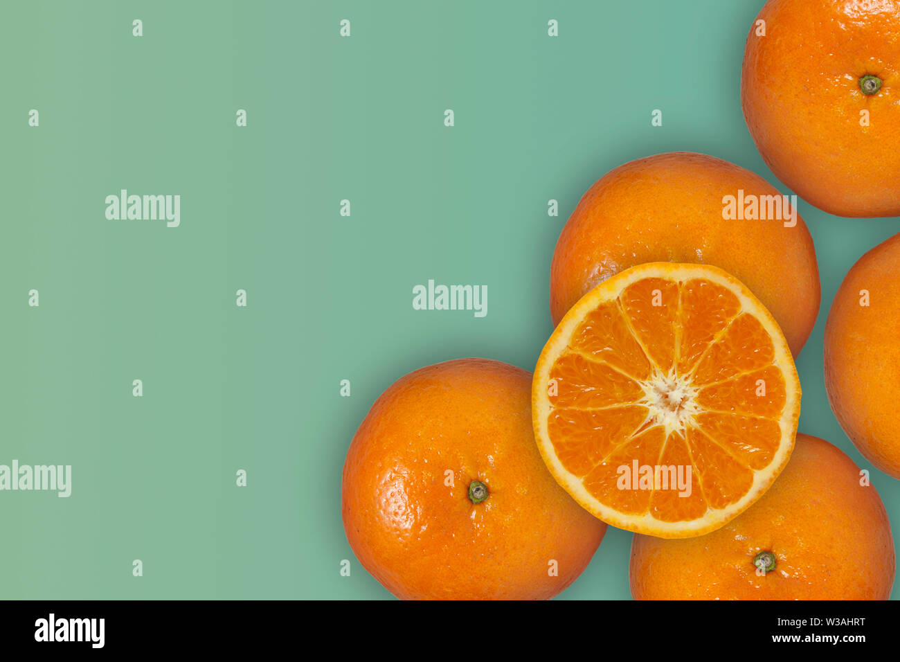 Orange Frucht mit der Hälfte isoliert auf einem grünen Hintergrund Pastell. Stockfoto