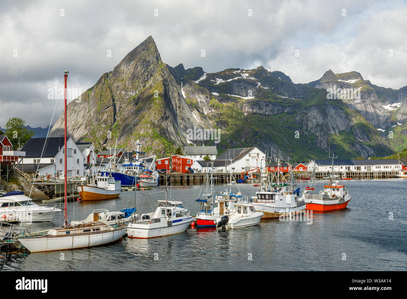Yachten und Boote mit Bergen im Hintergrund am Pier in Reine, Lototen Moskenesoya, Inseln,, Nordland County, Norwegen Stockfoto