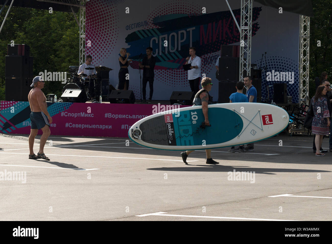 Athletischer Kerl mit Board führt vorbei an der Musik Plattform Moskau - Juni 2019. Die unterhaltung Aktion sportliche Moskau. Reklametafeln mit Hashtags in Russisch Stockfoto