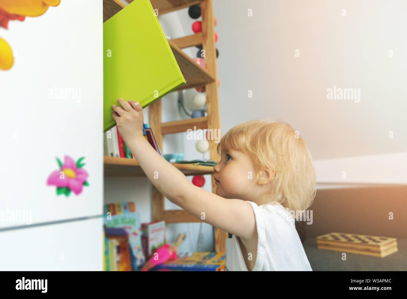 Kind nimmt ab Bücherregal zu Hause Stockfoto