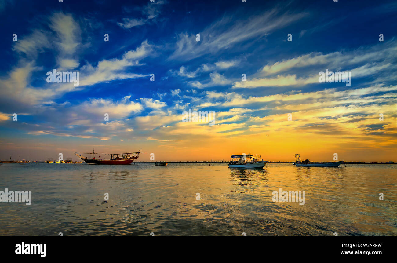 Schönen Sonnenaufgang Boot im Meer mit gelben und blauen Himmel Hintergrund. Dammam, Saudi-Arabien Stockfoto