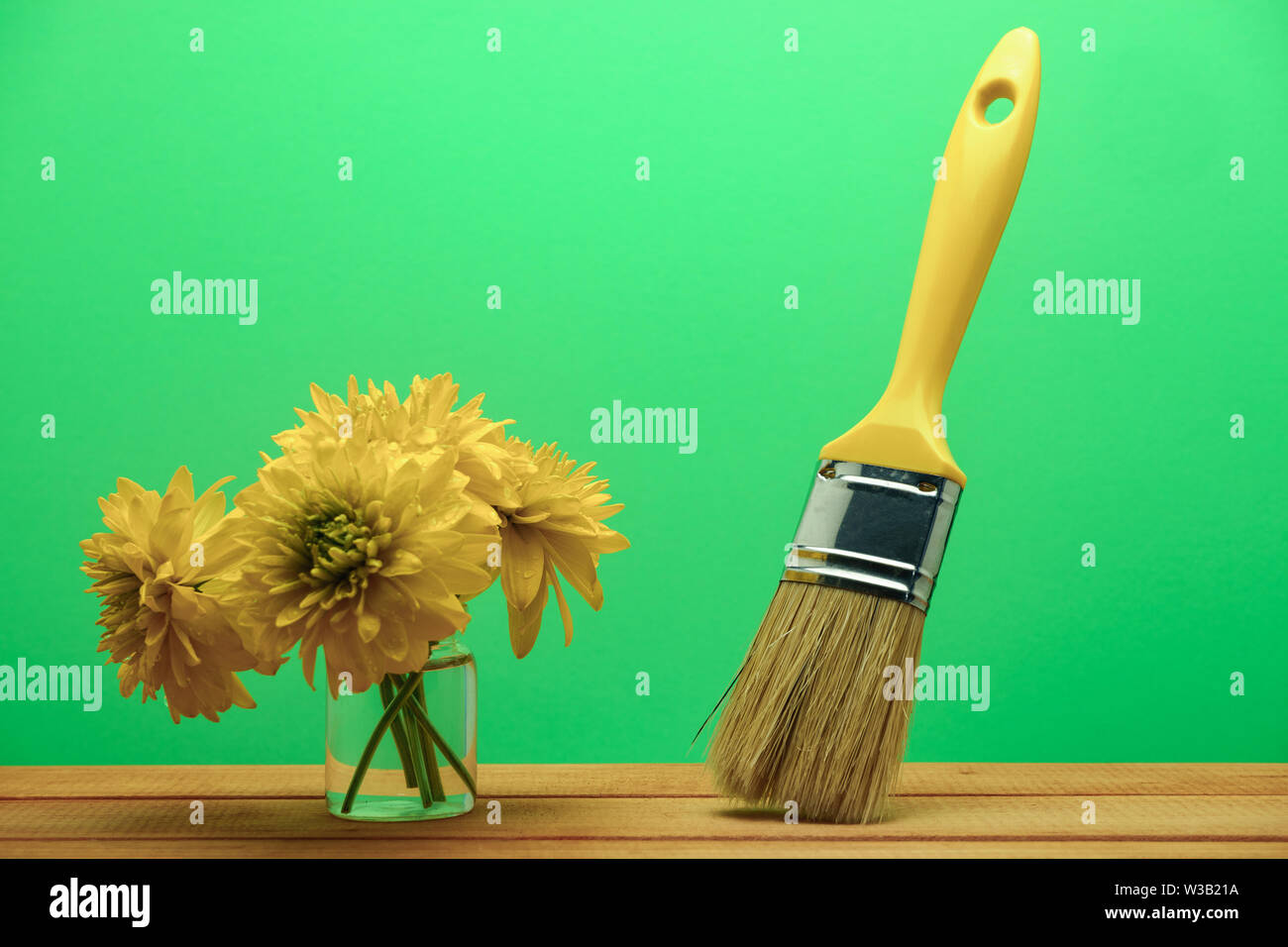 Neue Pinsel und Blumen in der Vase auf einem roten hölzernen Tisch. Wunderschöne grüne Wand Hintergrund hinter sich. Stockfoto