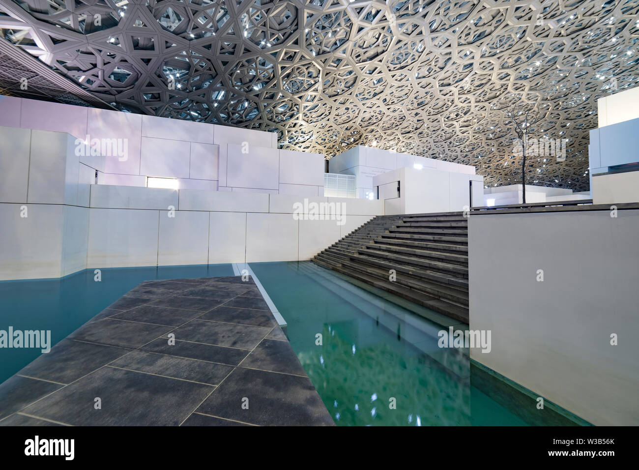 Louvre, Abu Dhabi, Vereinigte Arabische Emirate - Dezember 29, 2017: Erholungsgebiet mit eine Terrasse und ein Pool unter einem openwork vielschichtige Kuppel Stockfoto