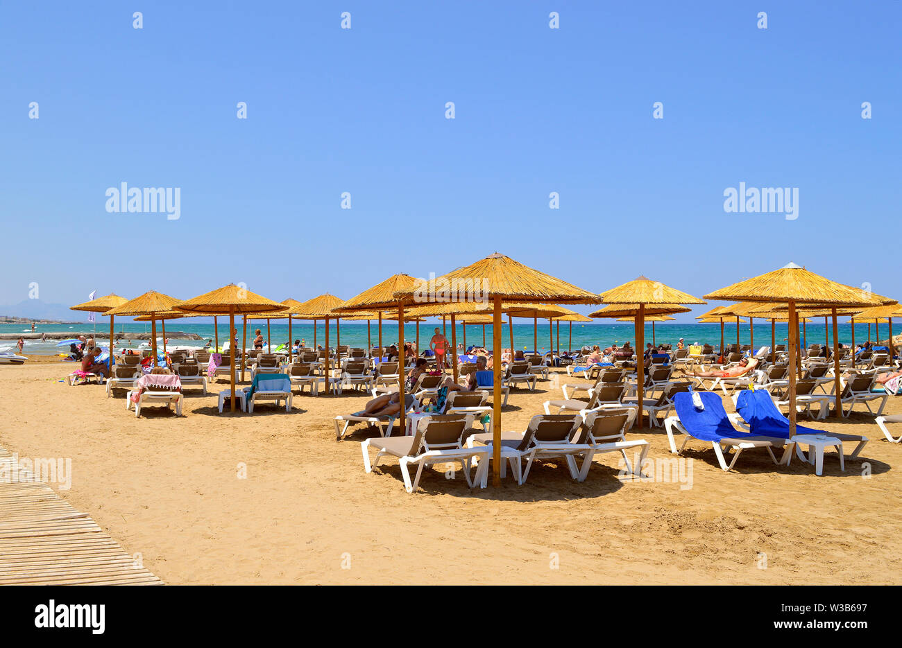 Touristen Sonnenbaden unter Sonnenschirmen am Strand von Gouves auf Kreta die grösste und populor der griechischen Inseln Stockfoto