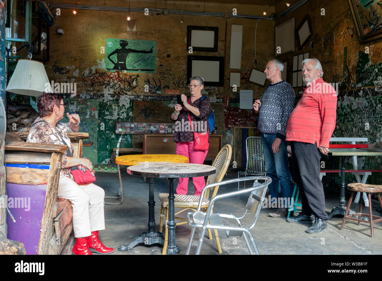 BUDAPEST, Ungarn - 09 April, 2019: Eine Gruppe älterer Touristen in coloful Kleidung selfies und Fotos mit Handys im Szimpla Kert pub ruinieren. Stockfoto