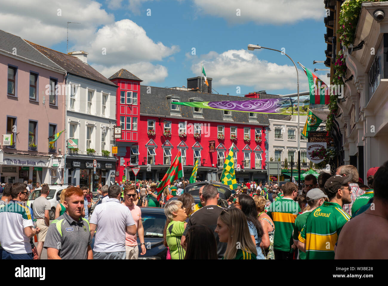 Spieltag in Killarney, County Kerry, Irland. Fans der gälischen Fußballfans von Kerry auf der College Street vor dem Spiel von Mayo und Kerry im Juli 2019. Geschäftige irische Stadt. Die Stadt Killarney war an einem sonnigen Tag voller Fußballfans. Stockfoto
