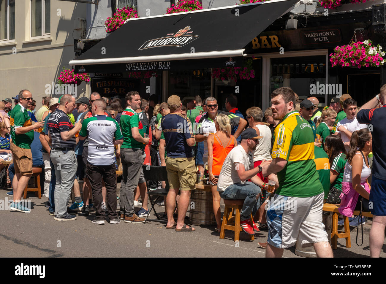 Spieltag in Killarney, County Kerry, Irland. Fans gälischer Fußballfans an einem Spieltag in den Killarney Streets genießen die Sonne vor der Speakeasy Bar in der High Street Stockfoto
