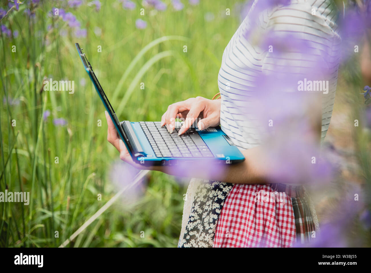 Attraktive asiatische Frau mit Laptop im Park. Stockfoto