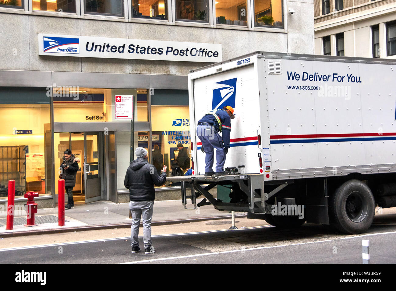 NEW YORK, USA - Dezember 14, 2018: USPS postman Auf der Mail Delivery truck in New York. USPS ist eine unabhängige agenc der US-Bundesregierung responsibl Stockfoto
