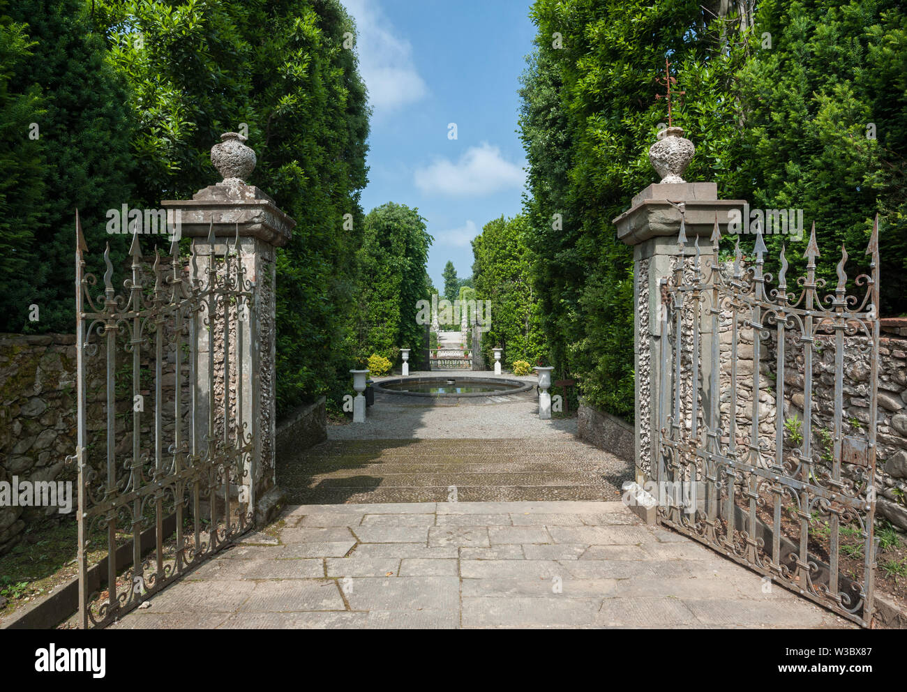 Marlia, Lucca, Italien - 2018, 25. Mai: ein Blick auf den Park der Villa Reale. Eine alte Eiserne Tor öffnet sich zum Garten. Stockfoto