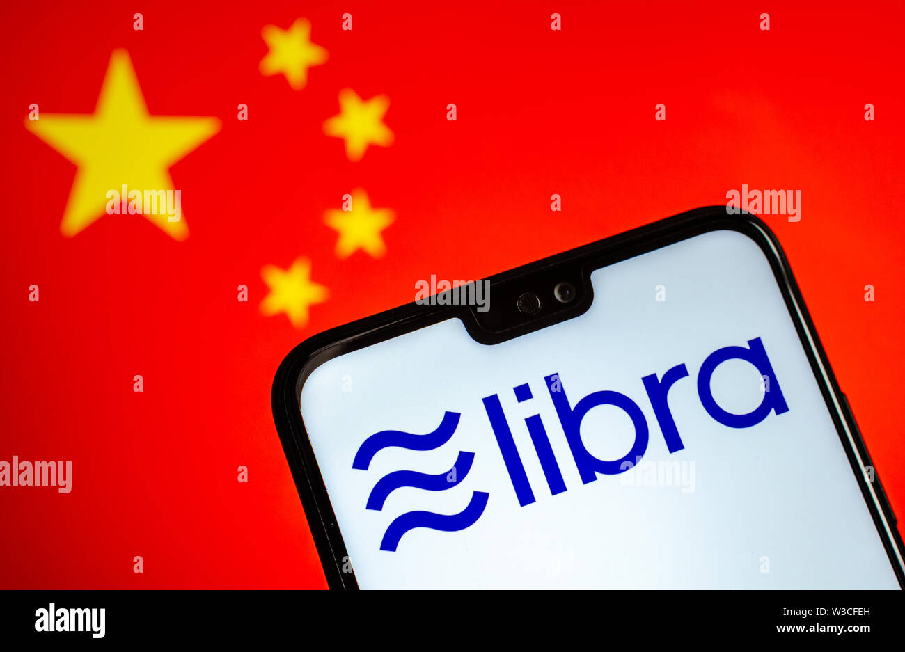 Facebook Waage crypto Währung Logo auf dem Smartphone und verschwommenes Flagge von China auf einen Laptop Bildschirm im Hintergrund. Konzeptionelle Foto. Stockfoto
