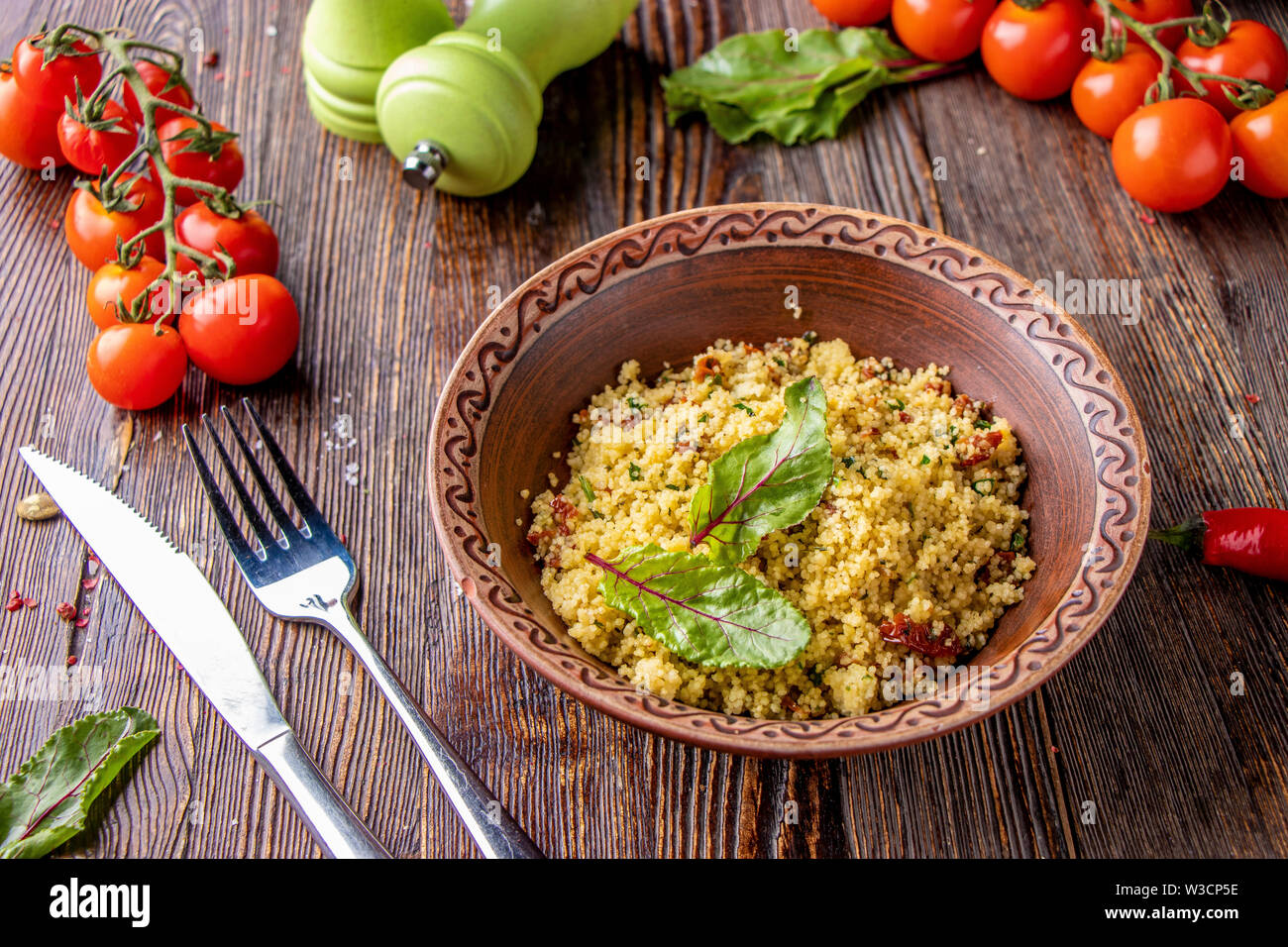 Couscous in Schüssel mit Olivenöl und getrockneten Tomaten auf Holzuntergrund, orientalische Küche, horizontale Foto, in der Nähe Stockfoto