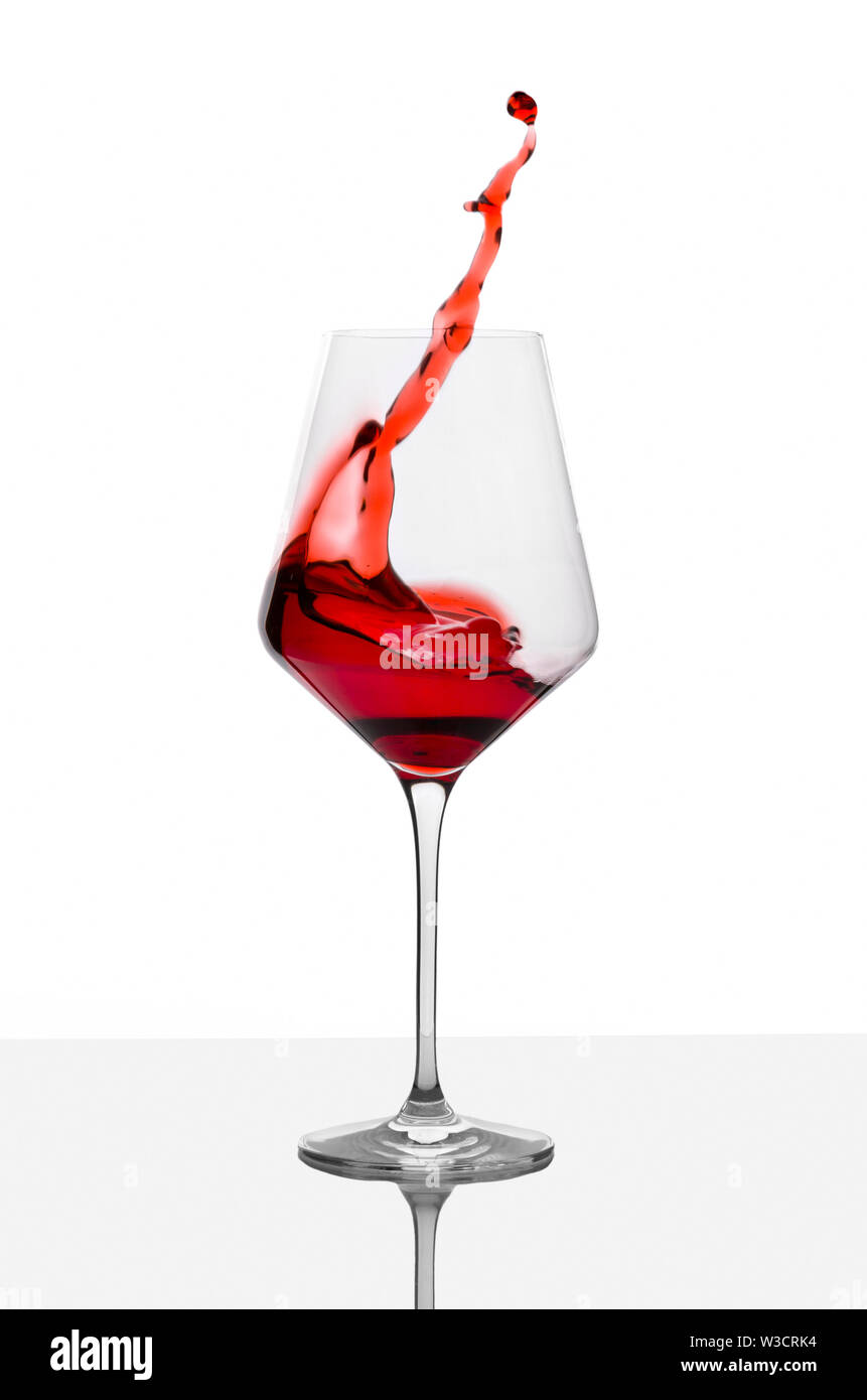 Glas Rotwein mit Spritzer auf weißer Tisch. Stockfoto