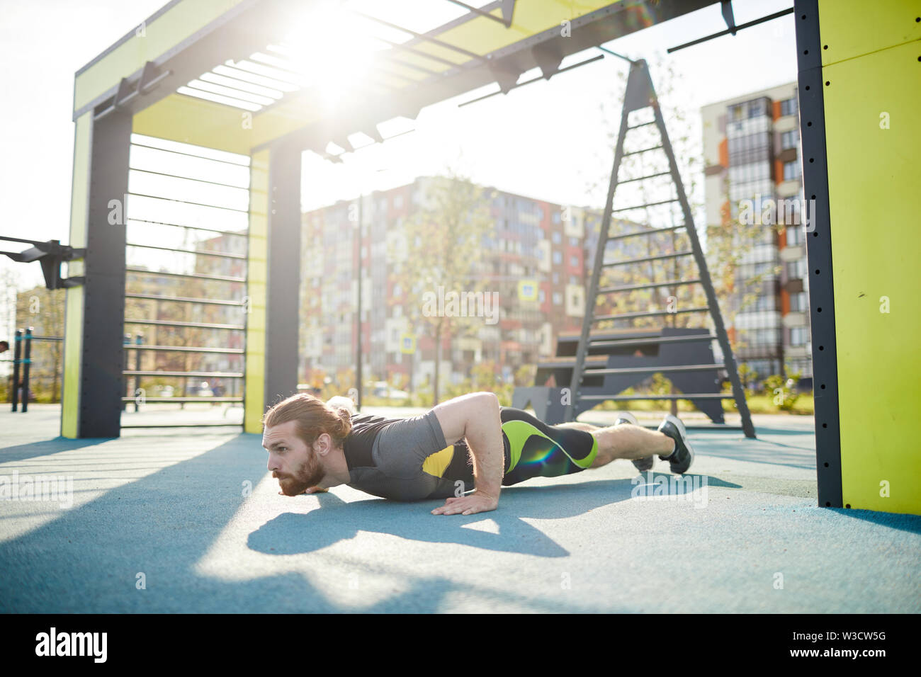 Ernsthafte muskulösen jungen bärtigen Mann konzentriert sich auf Push-ups Training im Freien Boden in der Stadt Stockfoto
