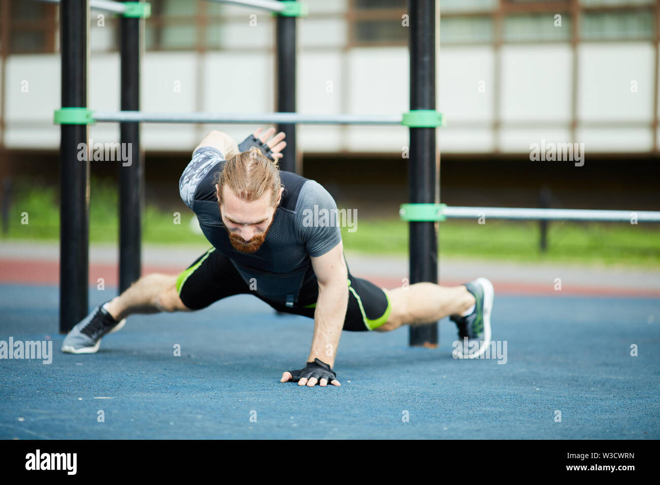 Starker junger bärtiger Mann in Sportkleidung, einer bewaffneten Push up im freien Training Boden konzentriert Stockfoto