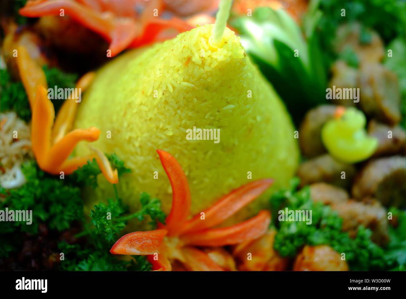 Ein traditionelles indonesisches Essen, das bei besonderen Veranstaltungen hergestellt wird. Nasi Tumpeng symbolisiert Dankbarkeit gegenüber Gott. Die gelbe Reisfarbe symbolisiert Wohlbefinden. Stockfoto